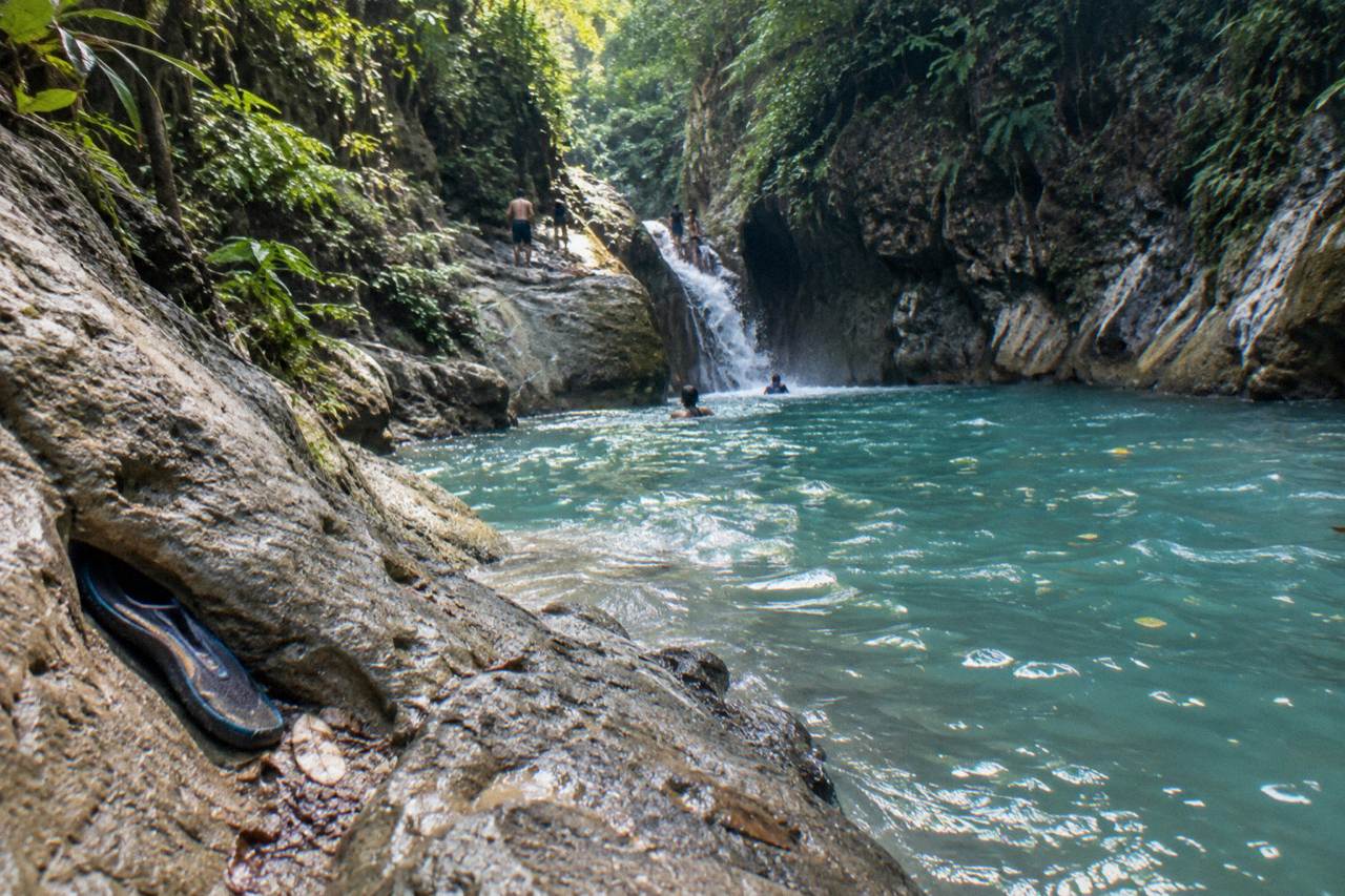 Turquoise waterfall pool at Damajagua framed by forested canyon walls