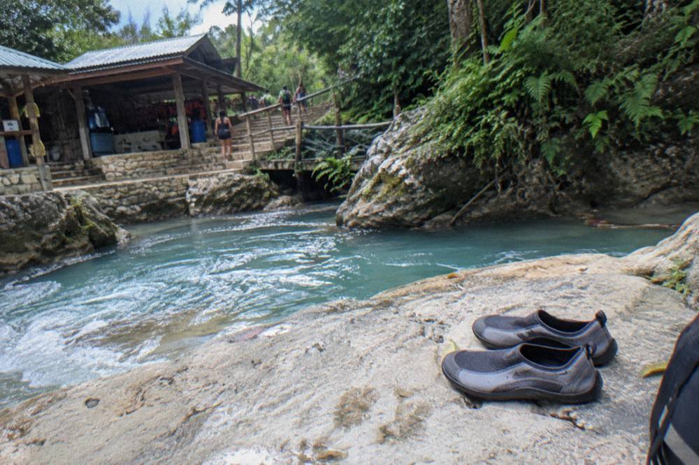 Closed water shoes drying on a sunny rock beside a flowing river